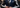 Man in a tailored navy suit with subtle armor elements representing confidence and modern style