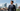 Man in a tailored navy suit overlooking the Raleigh skyline from a rooftop terrace.