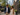 Stylish couple walking through Charlotte’s South End neighborhood in modern custom clothing with Uptown skyline in the background.