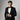 Model wearing tailored black tuxedo with bow tie on gray studio backdrop